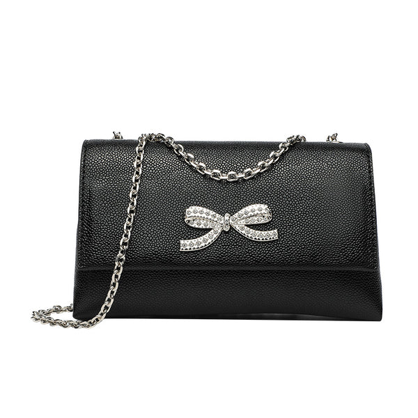 Structured rectangular flap crossbody bag with rhinestone bow and silver chain strap in pebbled finish, detail view 5