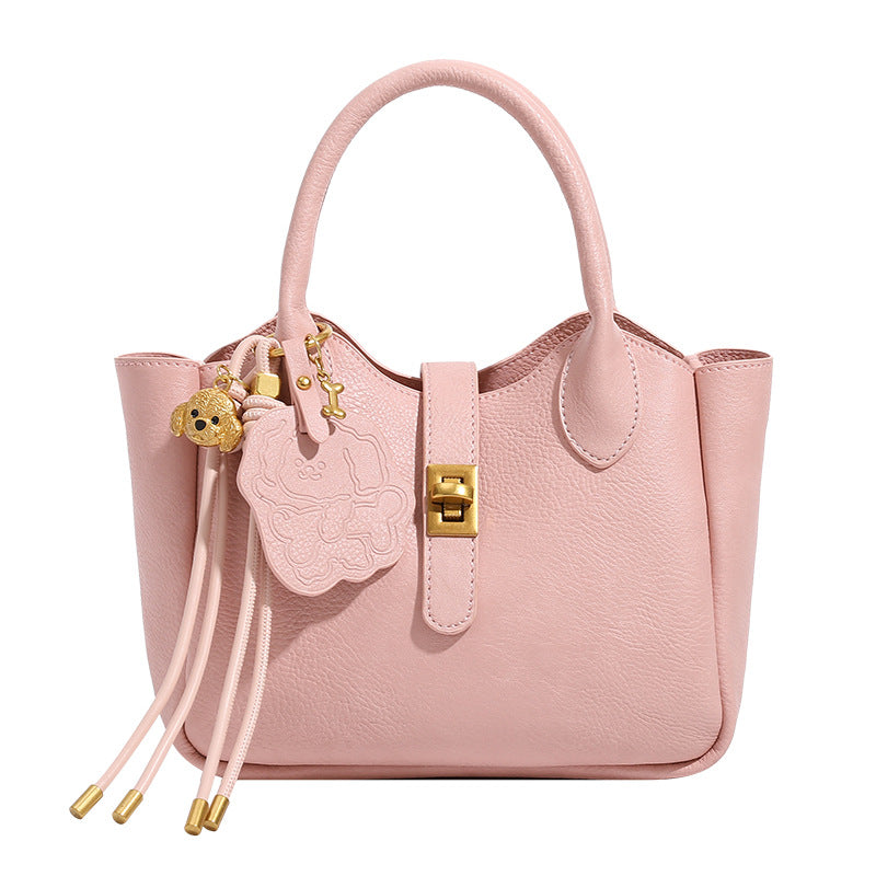 Small structured pebbled leather-look mini tote bag with gold-tone hardware, front toggle closure, knotted bear tassel charm