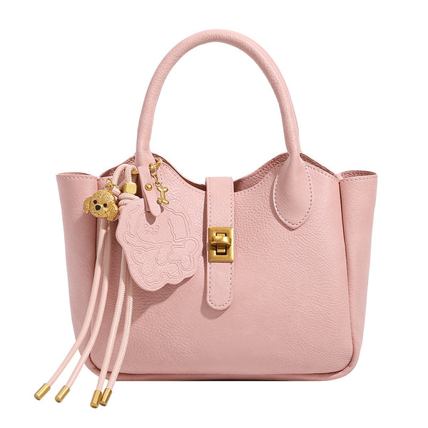 Small structured pebbled leather-look mini tote bag with gold-tone hardware, front toggle closure, knotted bear tassel charm
