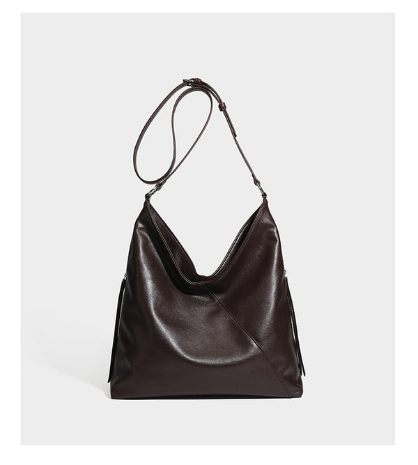 Large slouchy hobo shoulder bag with braided top handle, smooth glossy leather-look finish, and silver-tone ring hardware