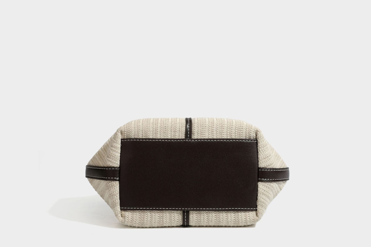 Cremefarbene geflochtene Tote-Bag mit dunkelbraunen Besätzen in Lederoptik, kontrastierenden weißen Nähten, zwei oberen Henkeln und abnehmbarem Schulter