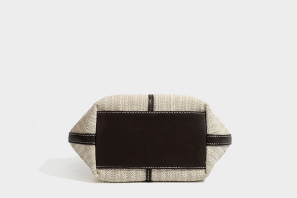 Cremefarbene geflochtene Tote-Bag mit dunkelbraunen Besätzen in Lederoptik, kontrastierenden weißen Nähten, zwei oberen Henkeln und abnehmbarem Schulter