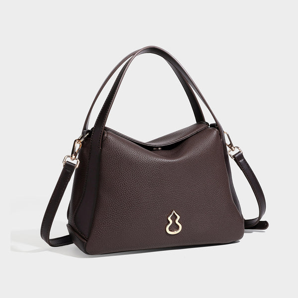 Structured pebbled leather-look shoulder bag with flap top, gold-tone emblem hardware, dual top handles, and detachable
