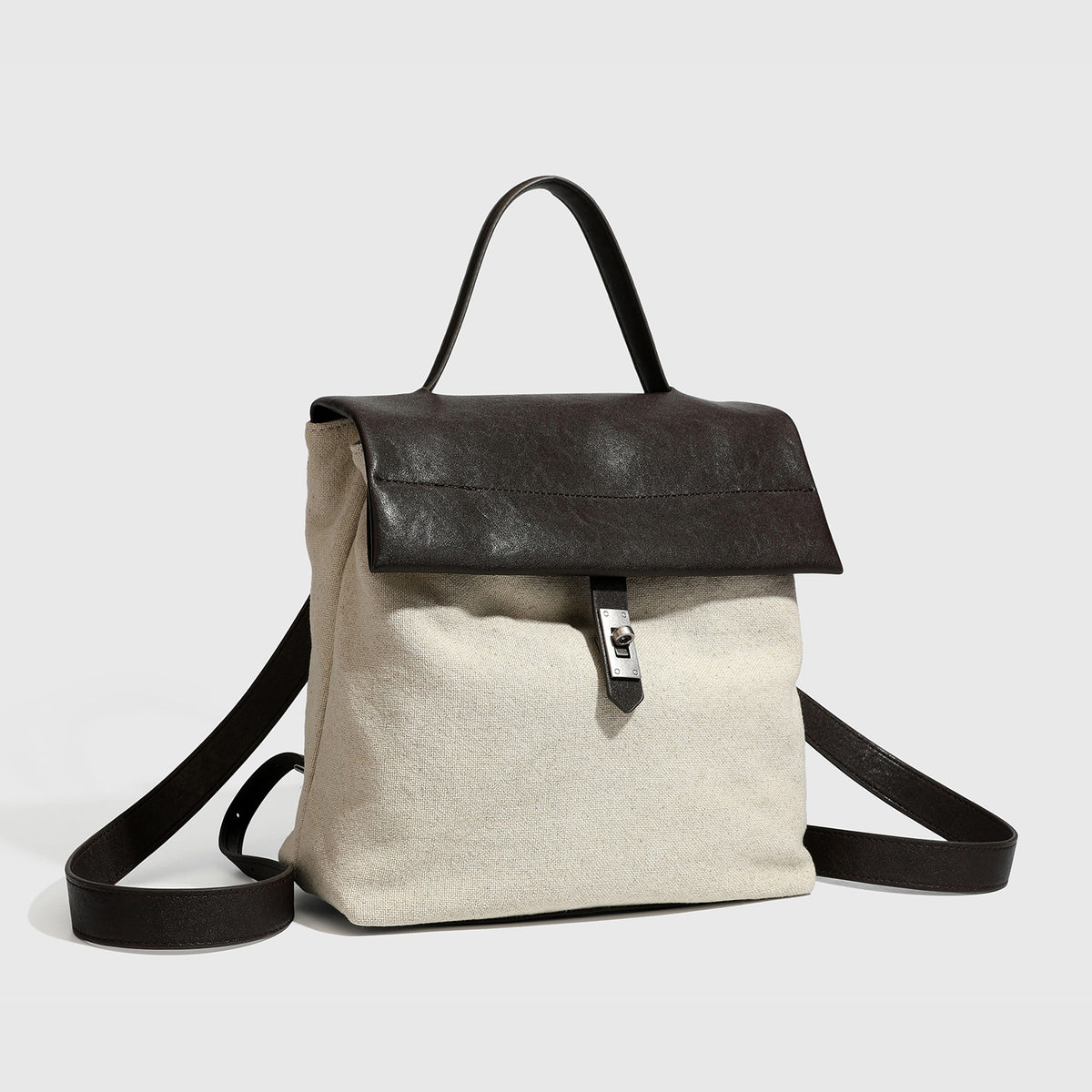 Structured beige woven canvas backpack handbag with black leather-look flap, turn-lock clasp, top handle, and flat shoulder
