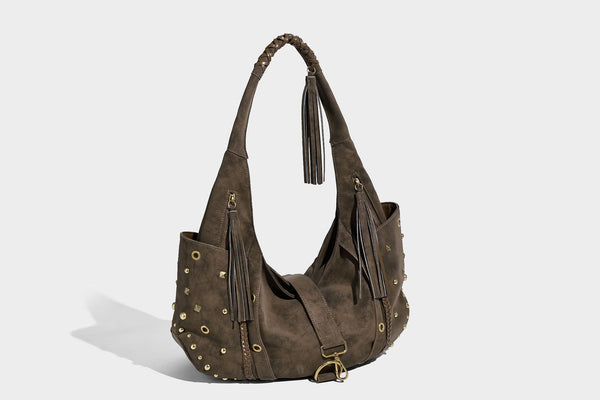 Slouchy crescent hobo bag in matte brown suede-like finish with gold-tone studs, grommets, braided top handle, tassel side
