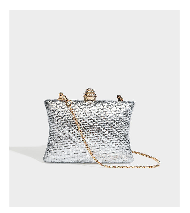 Small structured rectangular metallic woven-texture clutch bag with jeweled knob clasp and gold-tone chain strap, detail view