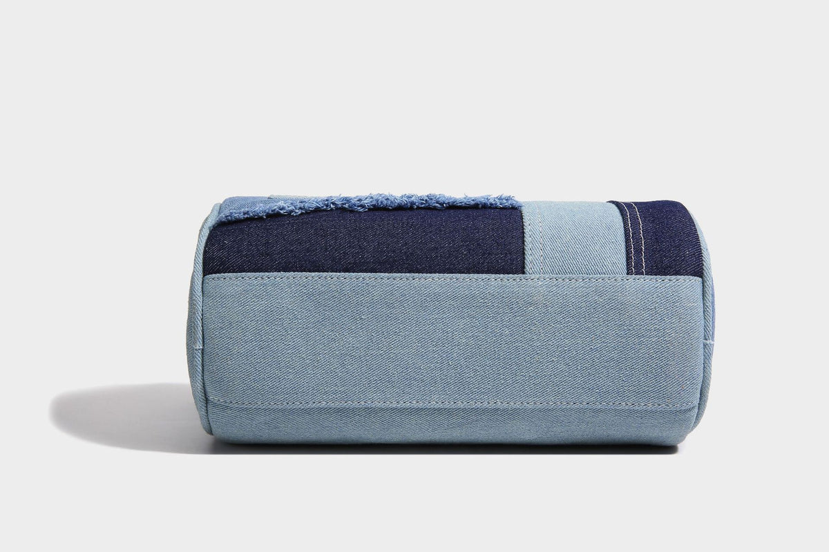 Mini barrel handbag in light and dark denim patchwork with frayed seam trim, dual top handles, top zip closure, and, detail