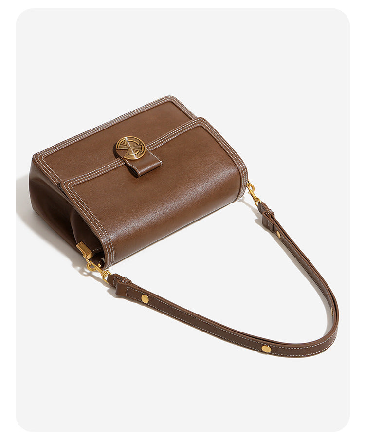 Structured flap shoulder bag with gold-tone circular turn-lock closure, white contrast stitching, and adjustable strap