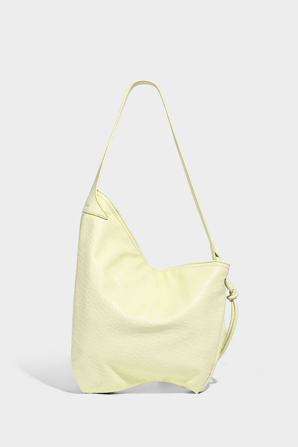 Slouchy hobo shoulder bag in pale yellow with slim strap, drawstring bead closure, and pink tulip floral charm, detail view