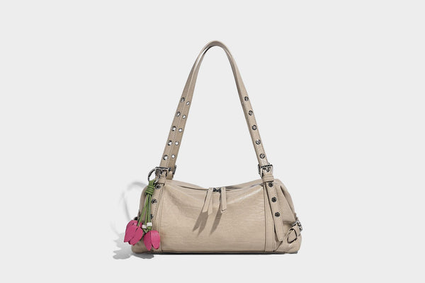 Pale yellow leather-look barrel bag with silver grommet-studded shoulder straps, top zip closure, and pink tulip floral