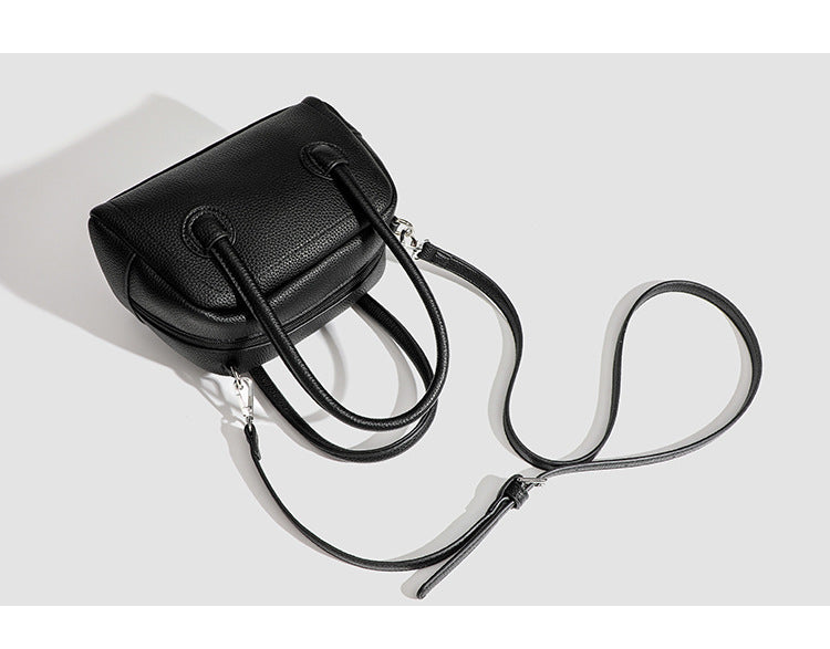 Mini-Boston-Tasche mit genarbtem Finish, zwei Henkeln, abnehmbarem und verstellbarem Crossbody-Riemen sowie silberfarbenen Beschlägen, Detailansicht