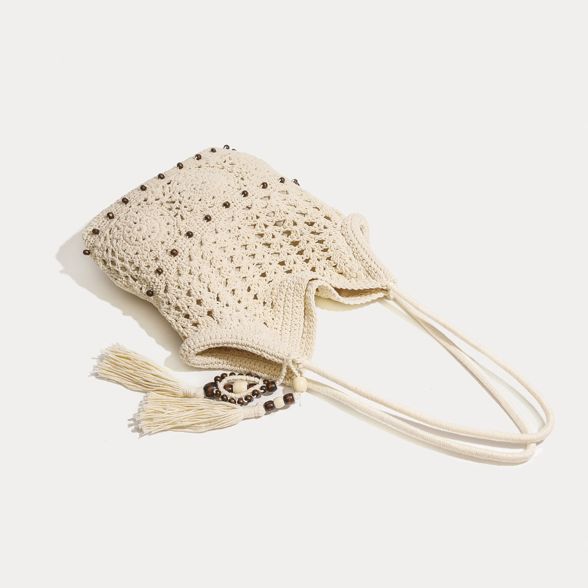 Cream openwork floral crochet tote bag with tassel and wooden bead charm and long rope shoulder straps, detail view 3