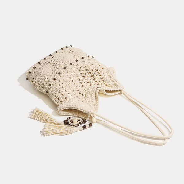 Cream openwork floral crochet tote bag with tassel and wooden bead charm and long rope shoulder straps, detail view 3