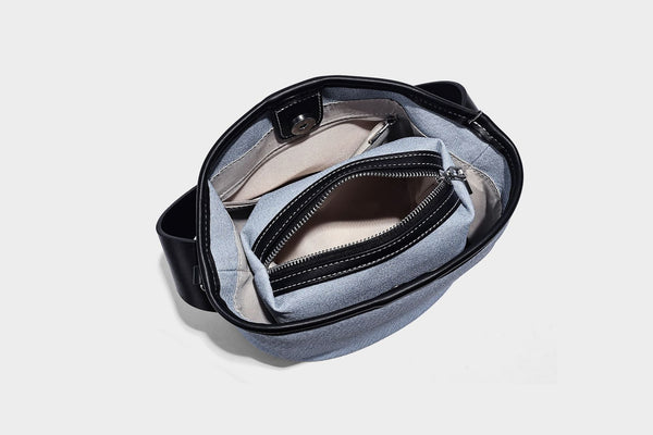 Hellblaue Bucket-Bag aus Denim mit schwarzem Besatz in Lederoptik, silberfarbenen Beschlägen, kurzem Tragegriff und langem verstellbarem Crossbody-Riemen
