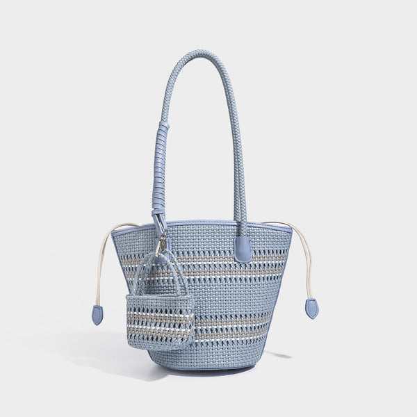 Structured woven bucket tote bag in pastel blue with braided shoulder strap, open lattice weave body, cream drawstring