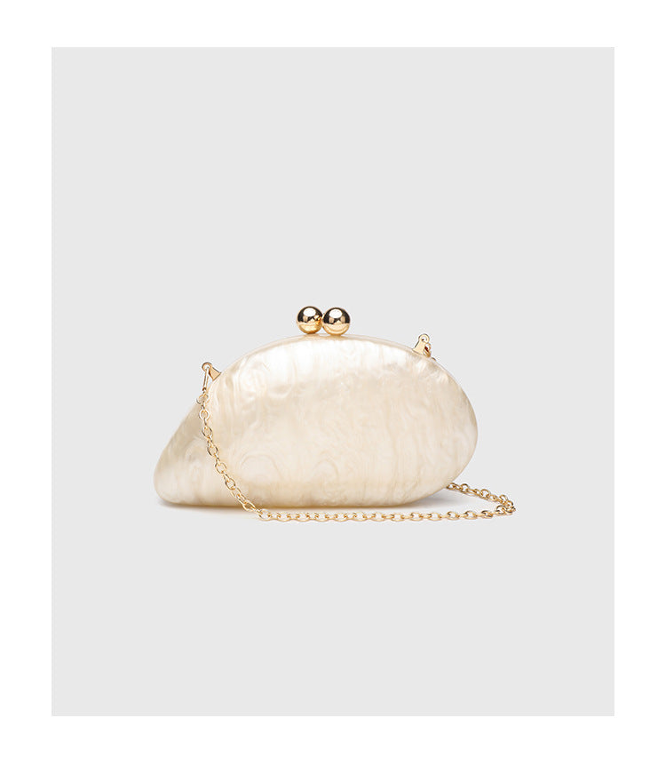 Ovale Hartschalen-Clutch in marmorierter Perlmuttoptik mit Verschluss aus zwei goldfarbenen Kugeln und goldfarbener Kettenriemen, Detailansicht