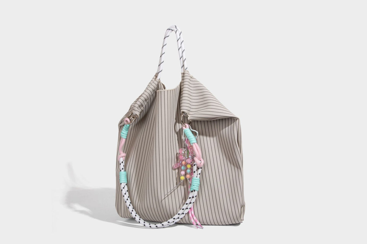 Slouchy pinstripe tote bag with braided rope handles, metal ring hardware, and colorful knotted rope charm, detail view 20