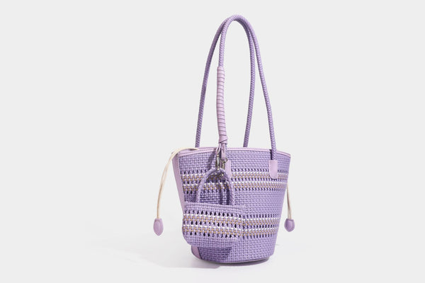 Light blue open-weave woven bucket tote bag with long braided shoulder straps, drawstring side ties, and attached mini pouch
