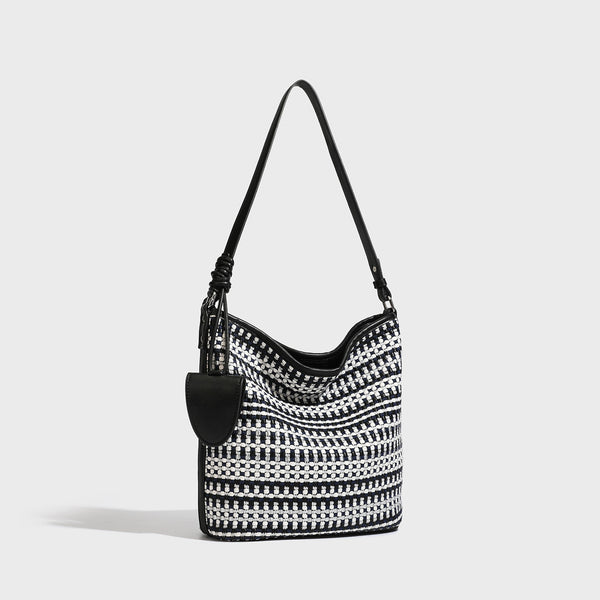 Woven stripe bucket shoulder bag in cream and dark brown with leather-look trim, knotted adjustable strap, and small shield