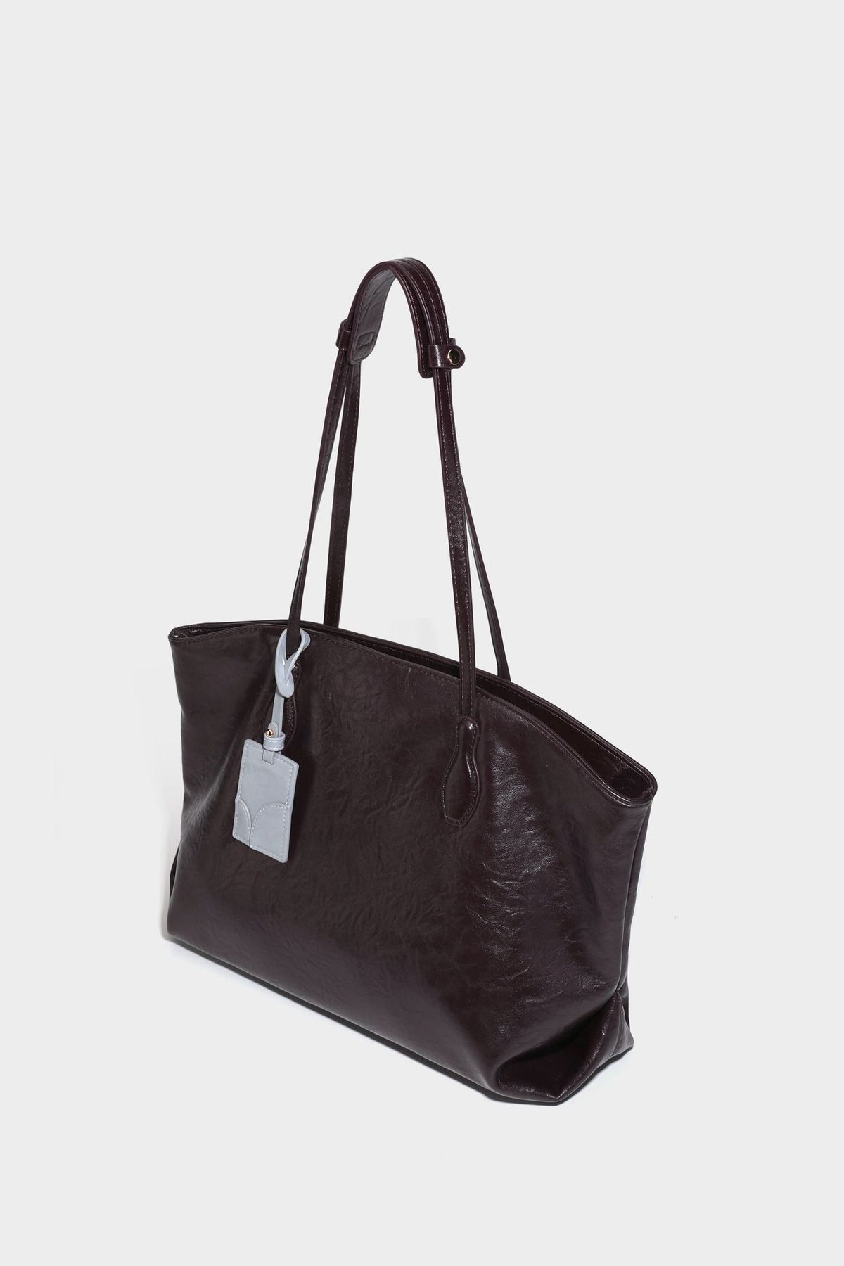 Übergroße, lässig fallende Tote-Bag aus glänzendem, geknittertem Lederimitat in dunklem Burgunderrot mit zwei langen Schulterriemen und kontrastierendem