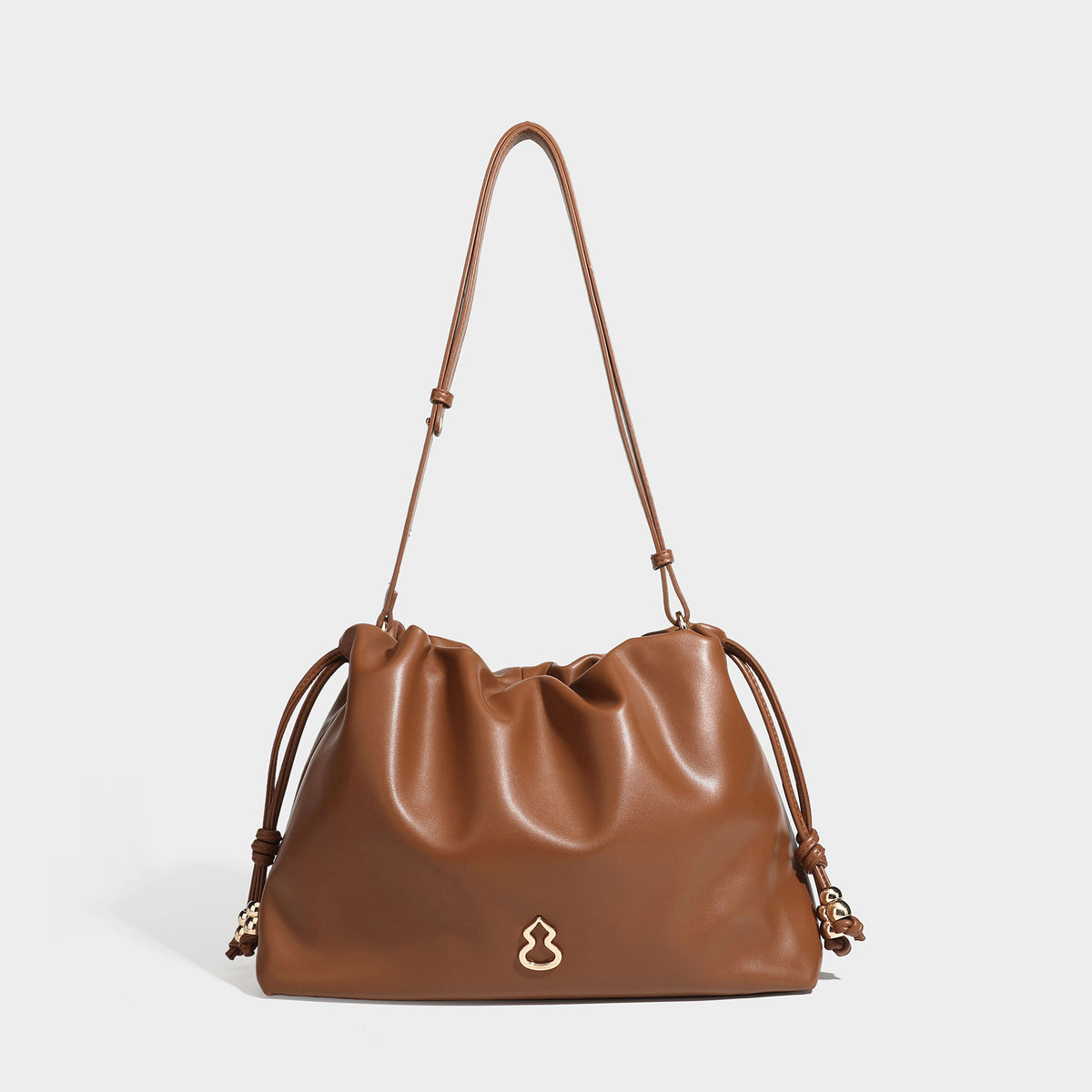 Slouchy ruched drawstring shoulder bag in smooth leather-look finish with gold-tone emblem and slim adjustable strap, detail