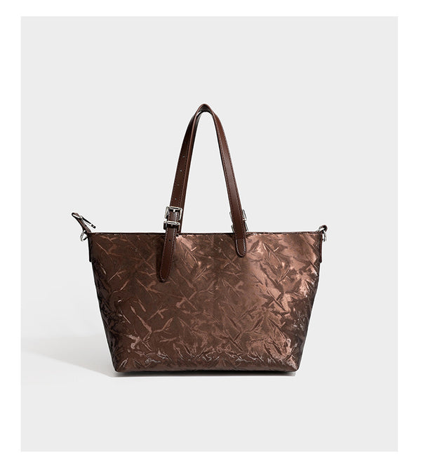 Glossy crinkled metallic-finish tote bag in brown with smooth leather-look top handles, silver-tone hardware, and attached