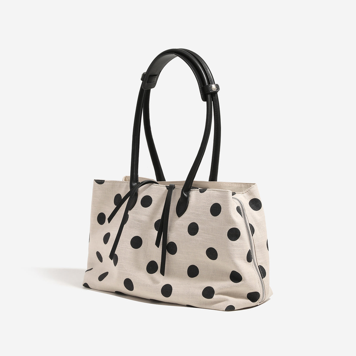 Cream canvas tote bag with black polka dots, rounded leather-look handles, and zip-top closure, detail view 4