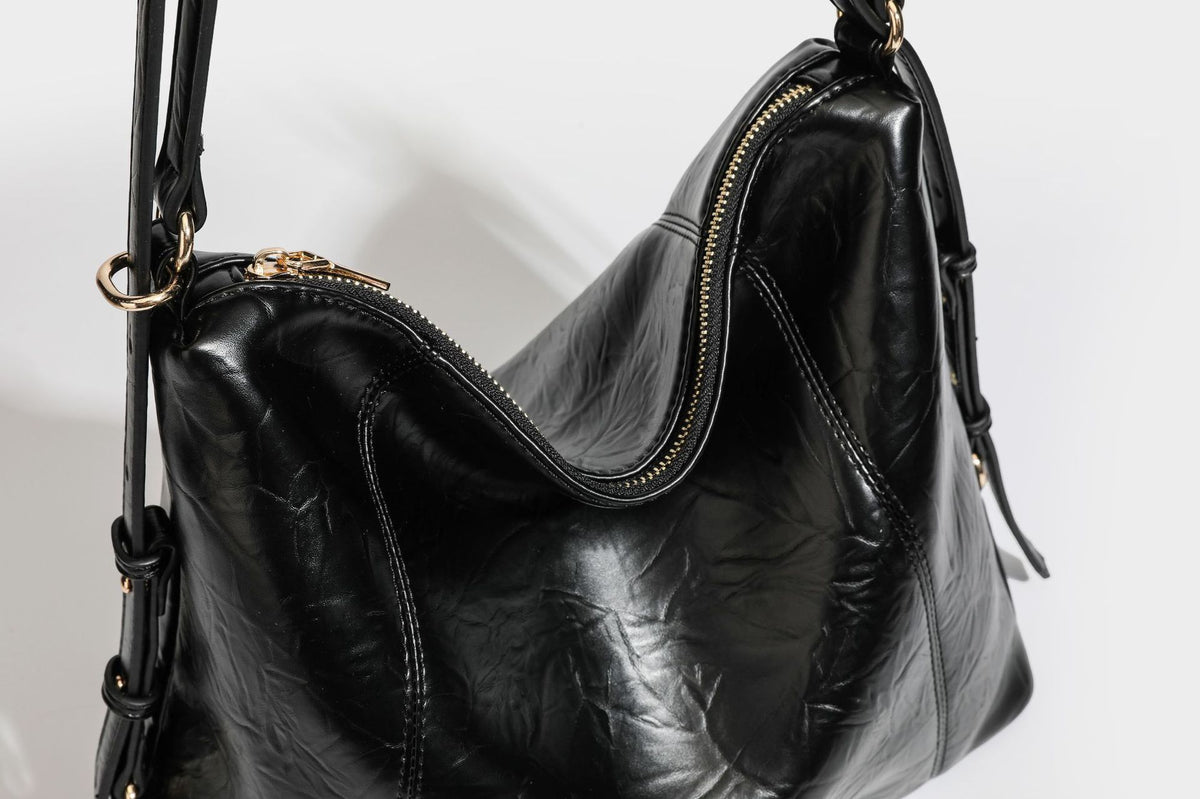 Große, lässig fallende Hobo-Schultertasche in glänzender, geknautschter Lederoptik mit goldfarbenen Beschlägen und langem, verstellbarem Riemen