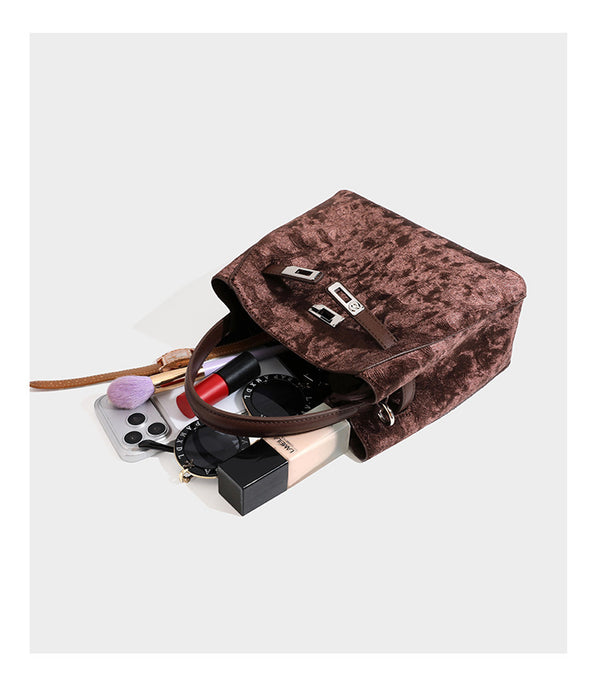Small structured bucket satchel in embossed velvet-texture fabric with silver turn-lock hardware, rounded top handle, and