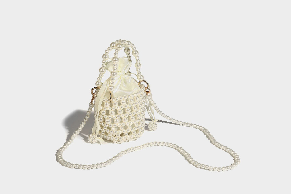 Elfenbeinfarbene Mini-Bucket-Bag aus Kunstperlen mit Satin-Innenbereich und Zugband, goldfarbenen Ringbeschlägen und gewölbtem Perlenhenkel an der Oberseite