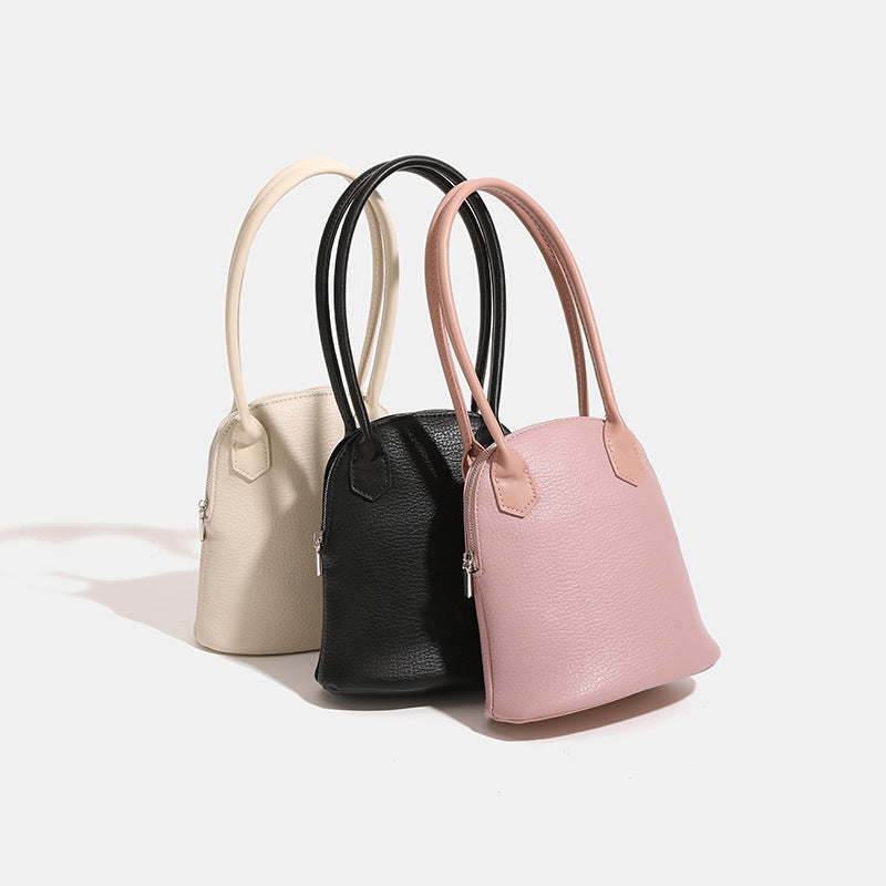 Rounded shell handbag with pebbled leather-look finish, dual top handles, and silver-tone zipper, detail view 2