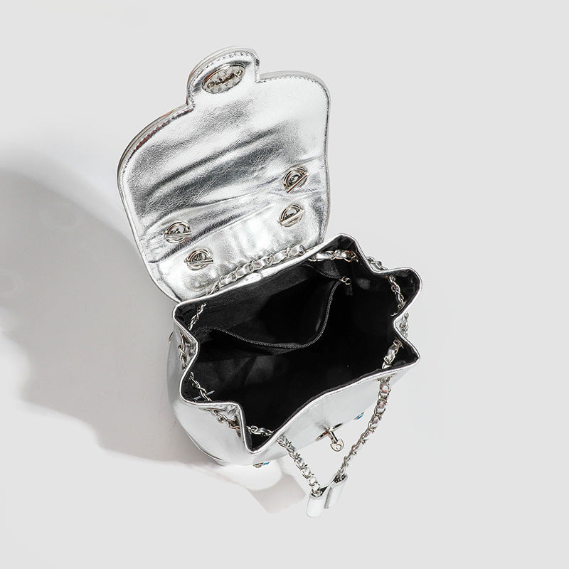 Kompakte silberfarbene Metallic-Rucksacktasche mit mehrfarbigen Kristallnieten, rundem Klappverschluss mit Drehverschluss und ineinander verflochtenem Silber