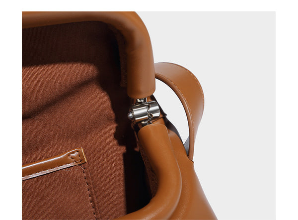 Compact structured baguette shoulder bag with smooth leather-look finish, zip top, and adjustable silver-buckle strap, detail