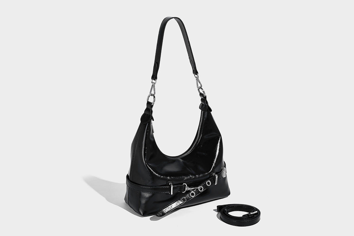 Glossy black slouchy hobo shoulder bag with silver-tone hardware, belt-style grommet strap at base, and long adjustable