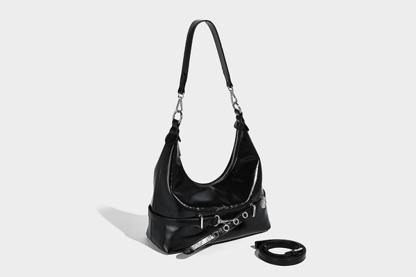 Glossy black slouchy hobo shoulder bag with silver-tone hardware, belt-style grommet strap at base, and long adjustable