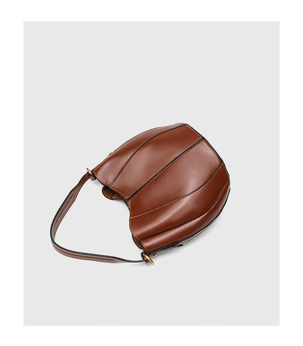 Smooth leather-look paneled bucket bag in brown with wide woven shoulder strap, gold-tone ring hardware, and detachable zip