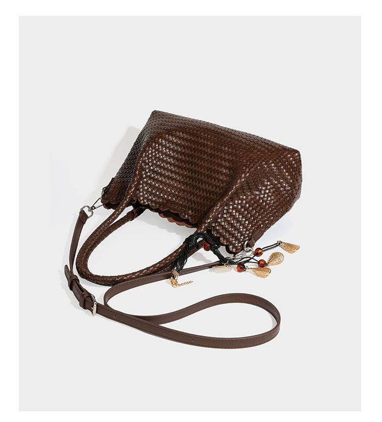 Strukturierter, glänzend geflochtener Shopper mit Muschelkantenabschluss am oberen Rand, geflochtenen Tragegriffen, abnehmbarem Crossbody-Riemen und Perlenquaste