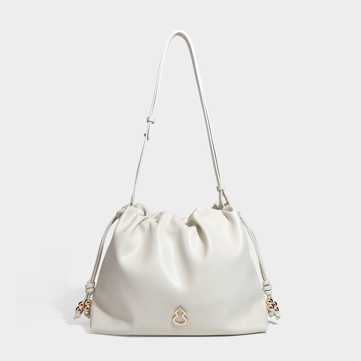 Slouchy ruched drawstring shoulder bag in smooth leather-look finish with gold-tone emblem and slim adjustable strap, detail