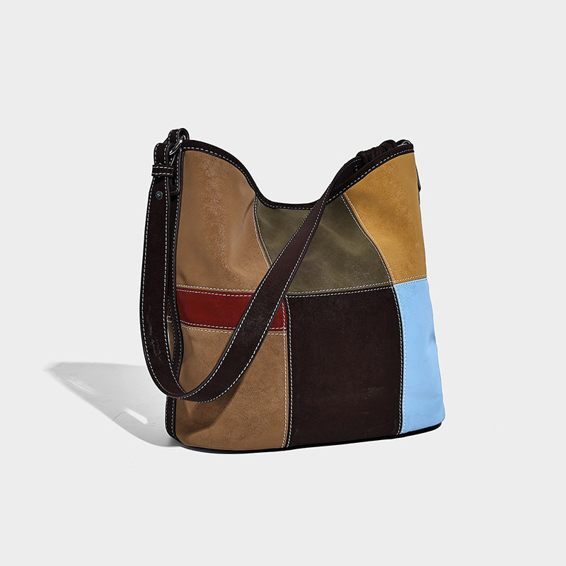 Slouchy patchwork bucket shoulder bag with dark brown, tan, mustard, olive, red, and light blue panels, contrast stitching