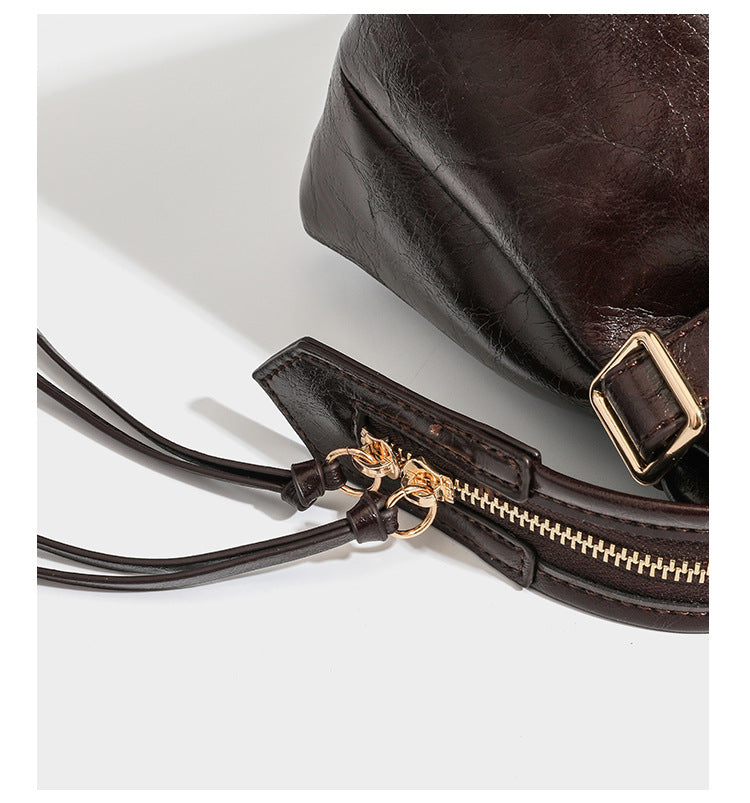 Glossy dark brown structured Boston satchel with heart-shaped lock charm, star pendant, rivet studs, multi-strap front panel