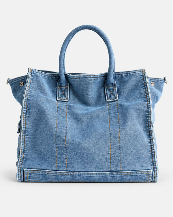 Large washed denim patchwork tote bag with snap-flap front pockets, rolled handles, and detachable shoulder strap, detail