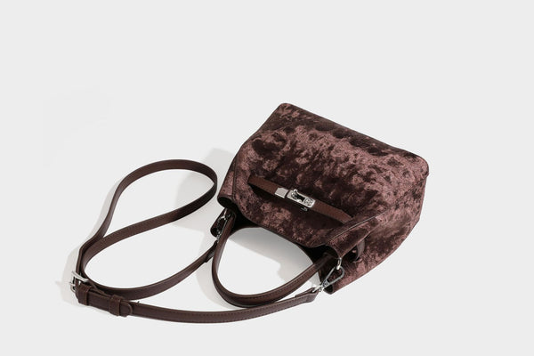 Small structured bucket satchel in embossed velvet-texture fabric with silver turn-lock hardware, rounded top handle, and