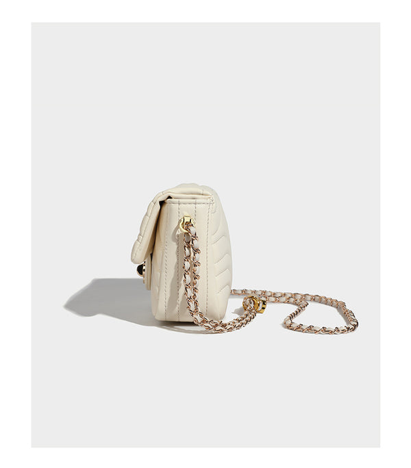 Compact cream quilted flap crossbody bag with wave stitching, gold-tone chain strap, and four-petal turn-lock clasp, detail