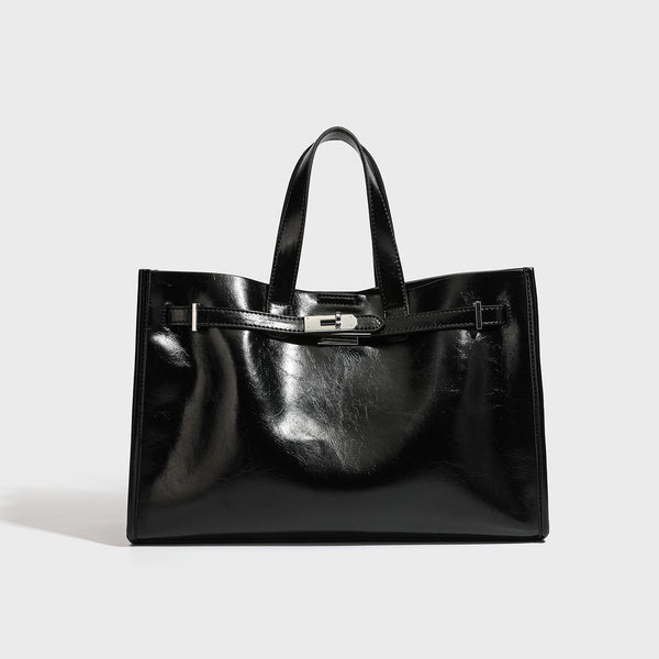 Strukturierte Tote-Bag in glänzender schwarzer Lederoptik mit Drehverschluss vorne, zwei Tragegriffen und abnehmbarem Schulterriemen