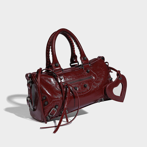 Glossy studded mini satchel bag with braided top handles, front zip pocket, heart charm, and detachable crossbody strap