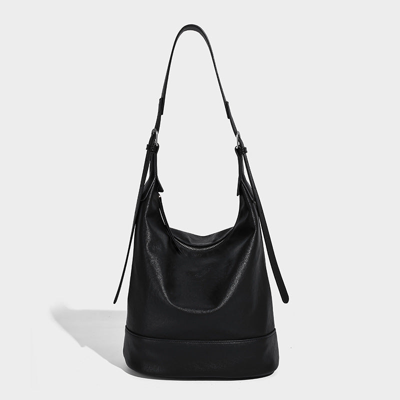 Slouchy bucket hobo shoulder bag in dark brown with glossy leather-look finish, top zip closure, and long adjustable, detail
