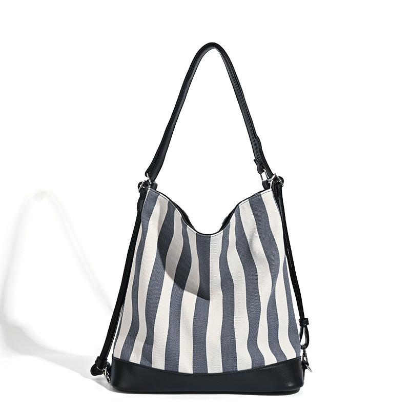 Wandelbarer Tote-Rucksack aus Canvas mit blau-weißen vertikalen Streifen, lederähnlichen Besätzen und silberfarbenen Metalldetails, Detailansicht