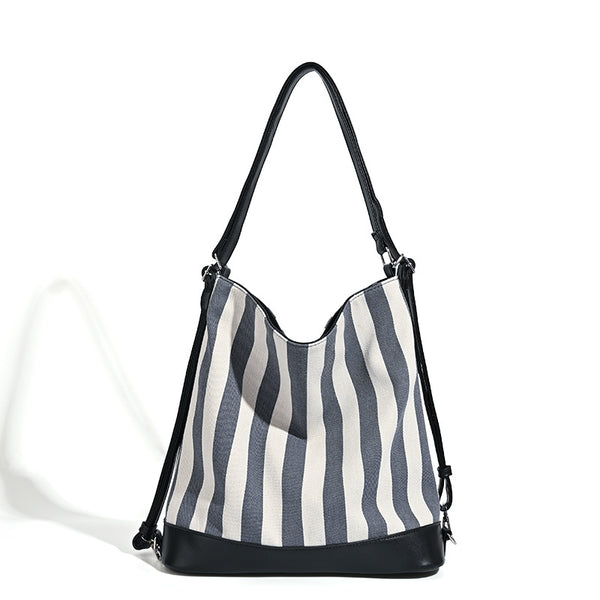 Wandelbarer Tote-Rucksack aus Canvas mit blau-weißen vertikalen Streifen, lederähnlichen Besätzen und silberfarbenen Metalldetails, Detailansicht