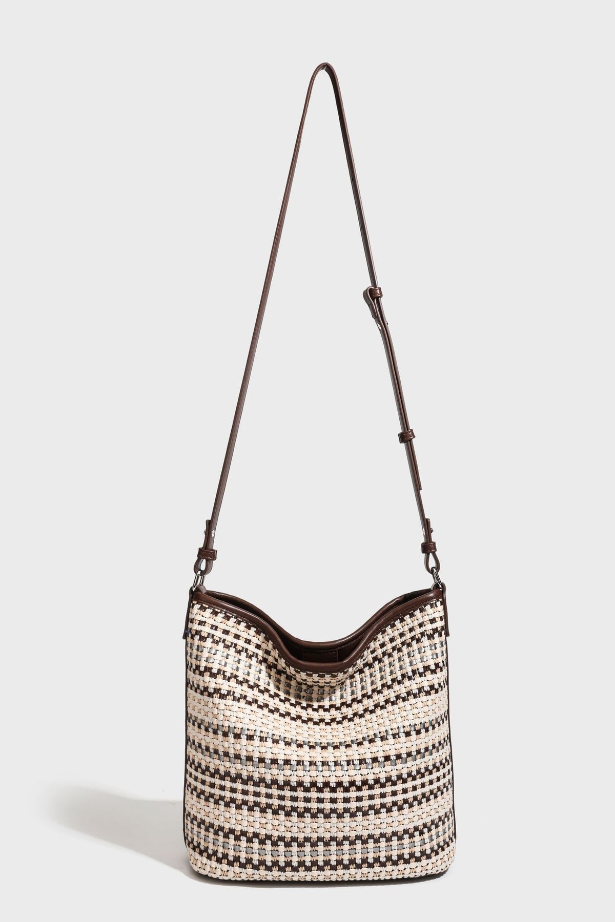 Woven stripe bucket shoulder bag in cream and dark brown with leather-look trim, knotted adjustable strap, and small shield