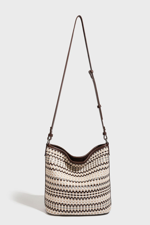 Woven stripe bucket shoulder bag in cream and dark brown with leather-look trim, knotted adjustable strap, and small shield